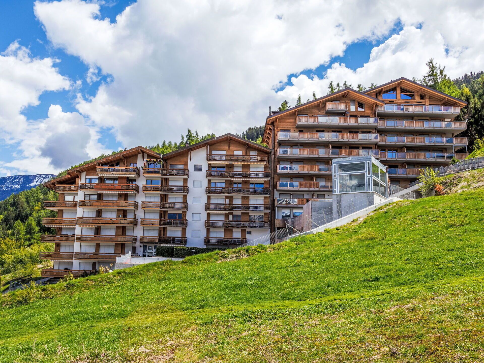 Ein mehrstöckiges Hotel mit Balkonen, gelegen an einem Hang mit Bergblick.