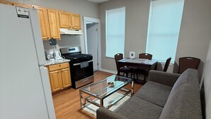 A compact living space with a kitchenette, a dining area, and a seating area with a sofa and a coffee table.