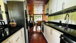 A kitchen with wooden ceiling, tiled floor, and white cabinets.