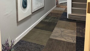 Un couloir doté d’un sol recouvert de moquette, d’un escalier et de trois œuvres d’art encadrées accrochées au mur.