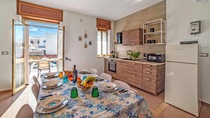 A modern kitchen with a dining area, featuring a large window, wooden cabinets, and a built-in microwave.