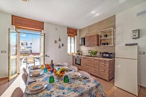 Une cuisine moderne avec un coin repas, dotée d’une grande fenêtre, de meubles en bois et d’un four à micro-ondes encastré.