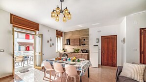 A modern kitchen with a dining area, a sofa, and a view of the outside.
