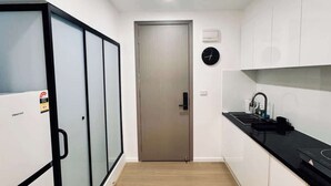 Een moderne keuken met een zwart aanrecht, witte kasten en een houten vloer.