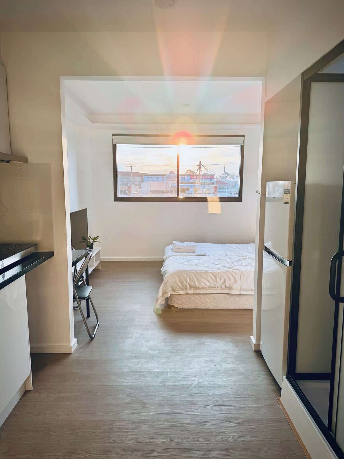 Une petite chambre comprenant un lit, un petit bureau et une kitchenette.