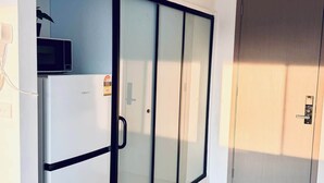 Een moderne kamer met een schuifdeurkast, een inbouwmagnetron en een deur met een greep.
