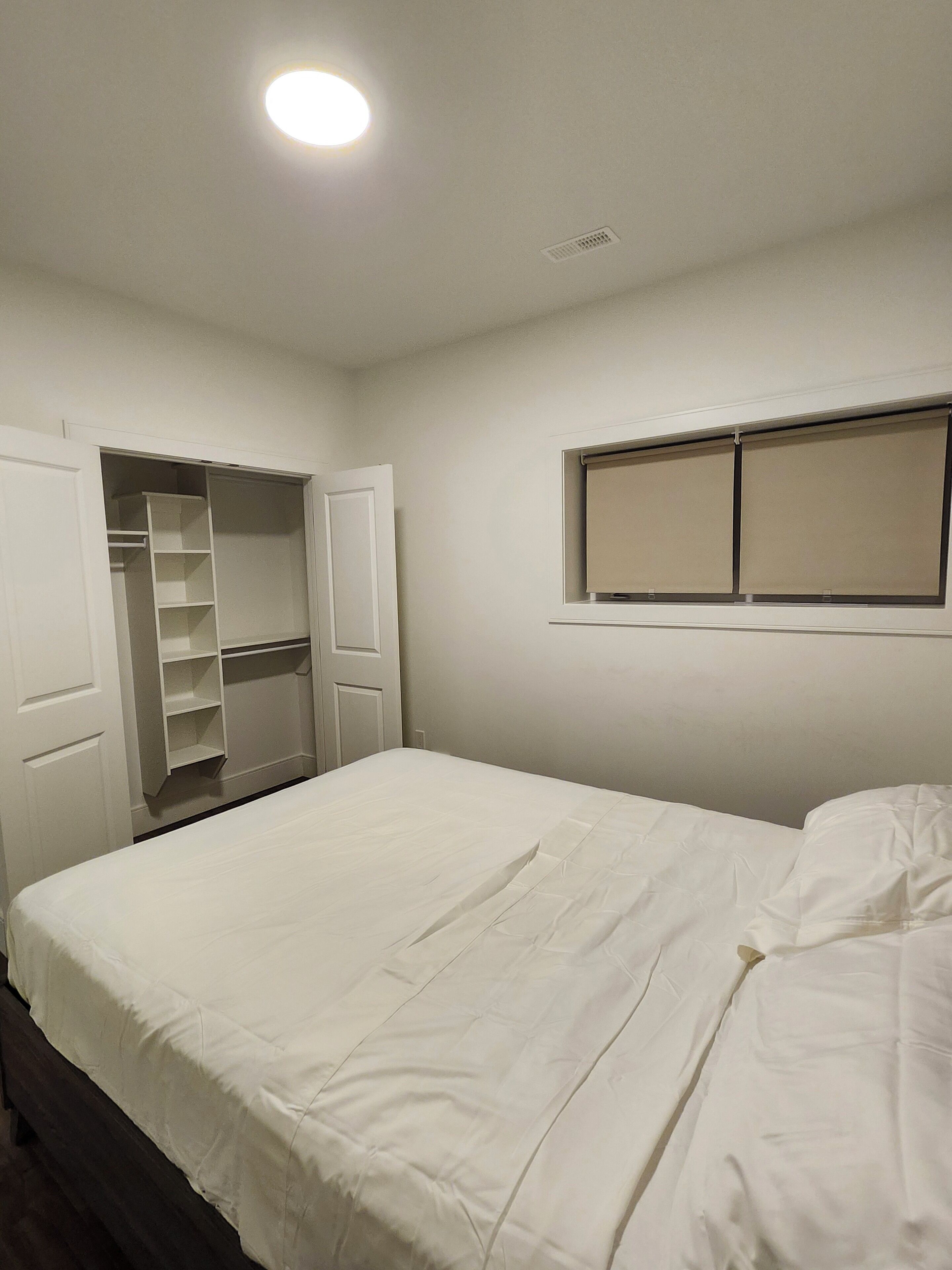 A bedroom with a bed, a wardrobe, and a window.