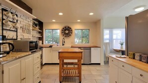 Une cuisine moderne avec des armoires blanches, une table en bois et une grande horloge murale.