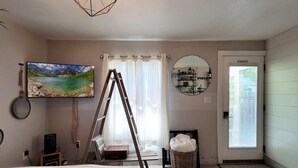 Une chambre à coucher avec un lit, une télévision, une échelle, un miroir, une cheminée et une fenêtre.