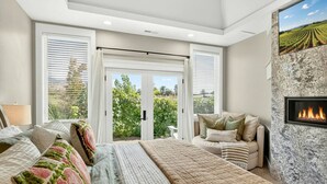 Une chambre à coucher avec un lit, un canapé, une cheminée et une vue sur l’extérieur.