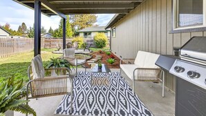 Un patio exterior con una parrilla, zona de estar y un tapete estampado.