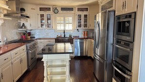 Una cocina con gabinetes blancos, electrodomésticos de acero inoxidable y una isla central.