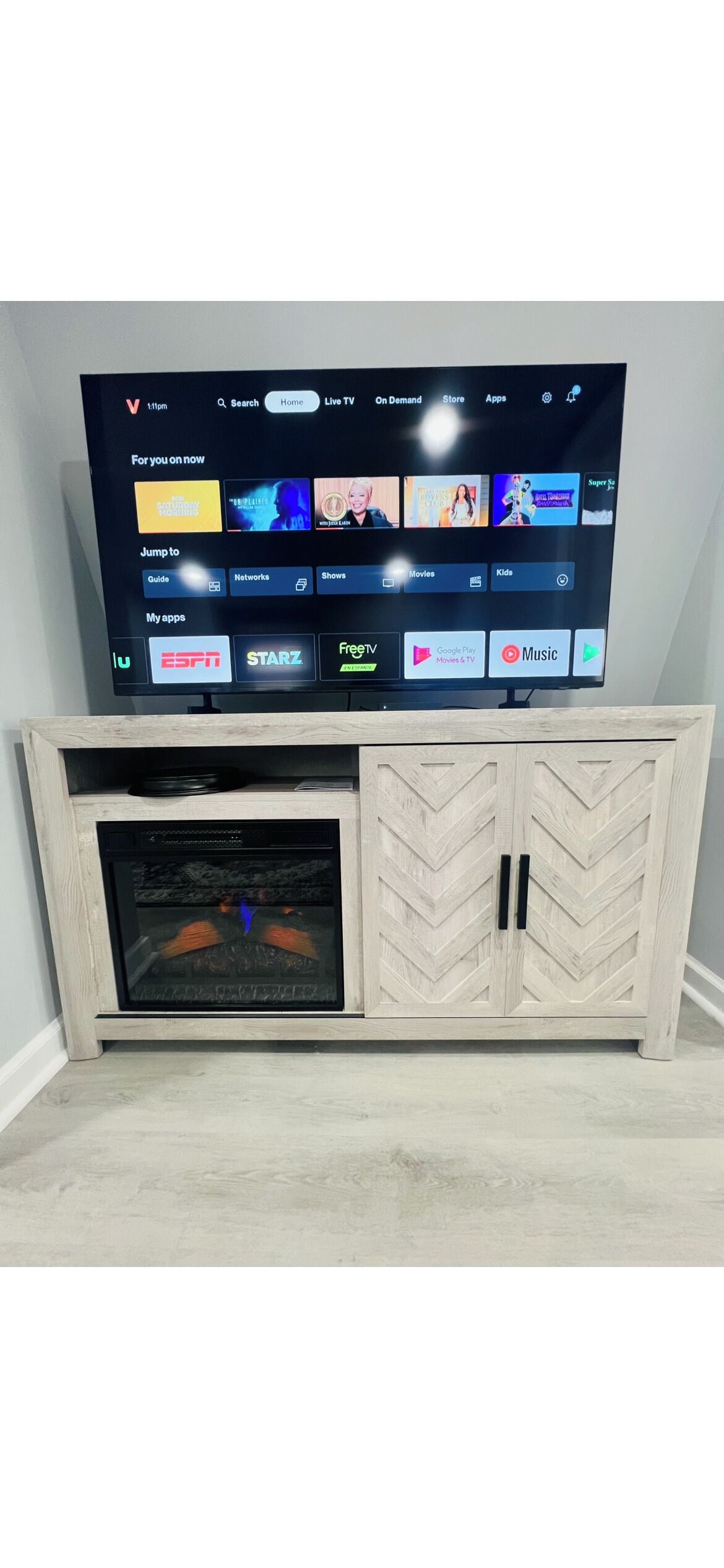 Un téléviseur à écran plat posé sur un meuble en bois, avec une cheminée intégrée en dessous.