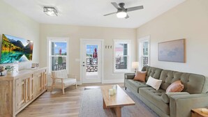 A living room with a sofa, a coffee table, a TV, and a door leading to an outdoor area. - Stay in all five Canopies (Ottawa)