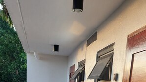Ein Korridor mit Fliesenboden, einer Holztür und einem Fenster mit Metallgitter.