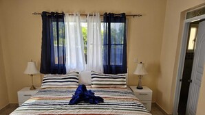 Una habitación de hotel con una cama grande, dos mesitas de noche y una puerta.
