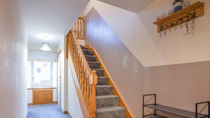 Un escalier avec des balustrades en bois et des marches recouvertes de moquette, menant à un palier.