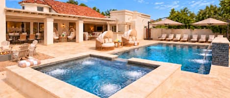 A pool area with hot tubs, lounge chairs, and a covered patio.