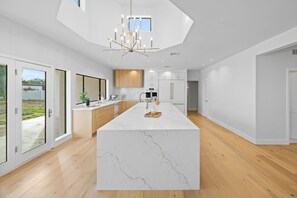 A modern kitchen with a large island, wooden cabinets, and a view to the outside. - The Tiercel – 20-Person Spa, Heated Salt Pool, Pickleball, 2025 Renovation (Scottsdale)
