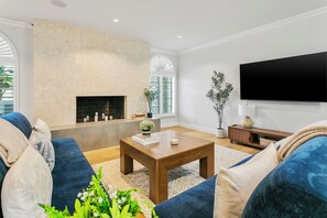 Uma sala de estar moderna com lareira, televisão de tela plana e um sofá grande.
