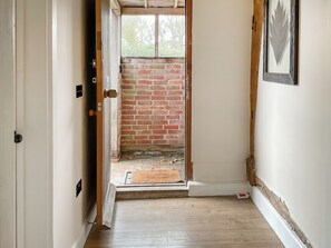 A hallway with a brick wall, a wooden door, and a window. - Smallbrook cottage - UK50922 (Sailsbury)