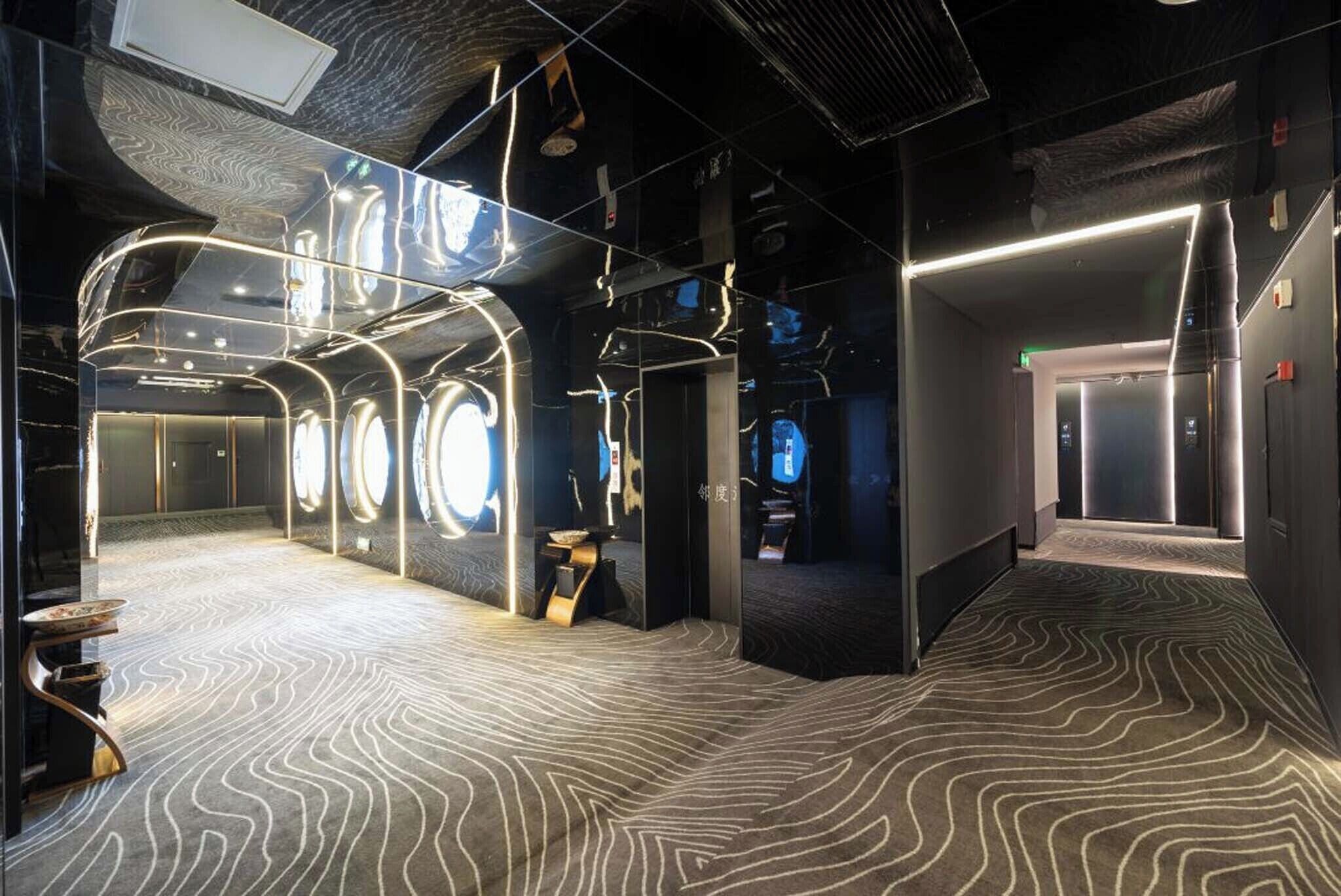 Een modern interieur met een golvend tapijt, een glazen wand met ronde verlichtingsarmaturen en een lift.