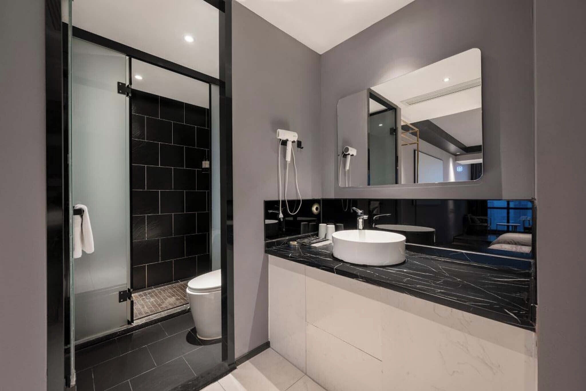 A modern bathroom with a glass-enclosed shower, a white sink, and a large mirror.