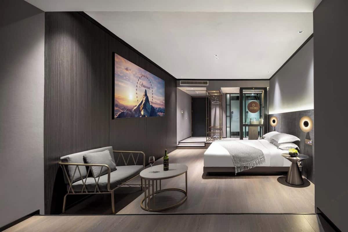 Une chambre d’hôtel moderne, équipée d’un lit, d’un coin salon avec une table et d’un grand tableau au mur.