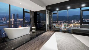 A modern bathroom with a freestanding bathtub, a large window offering a city view, and a seating area with a table and chairs. - Chongqing Lingdu Gaokong Jiangjing Hotel (Chongqing)