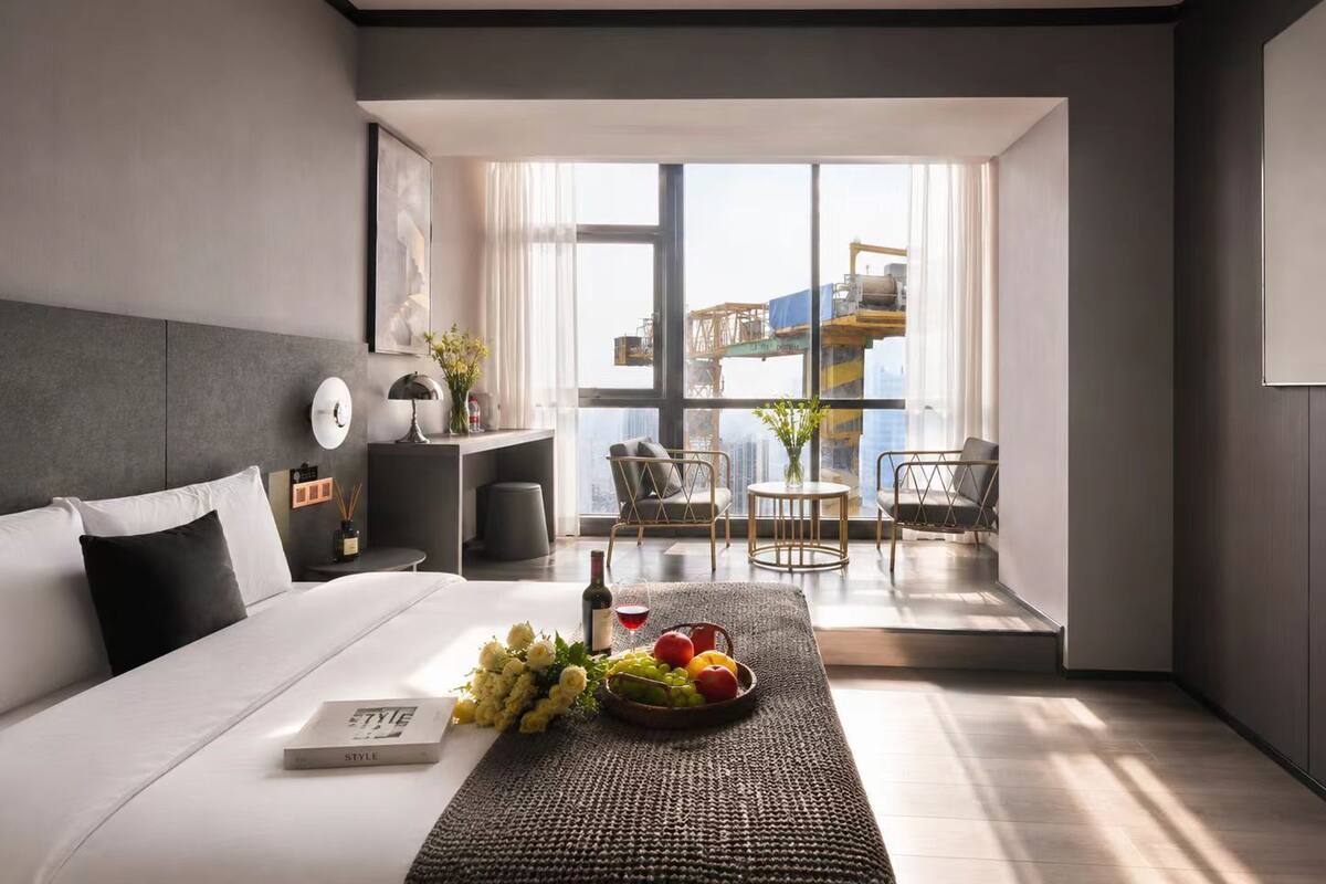 Une chambre d’hôtel moderne dotée d’un grand lit, d’un bureau, d’une chaise et d’un balcon offrant une vue sur la ville.
