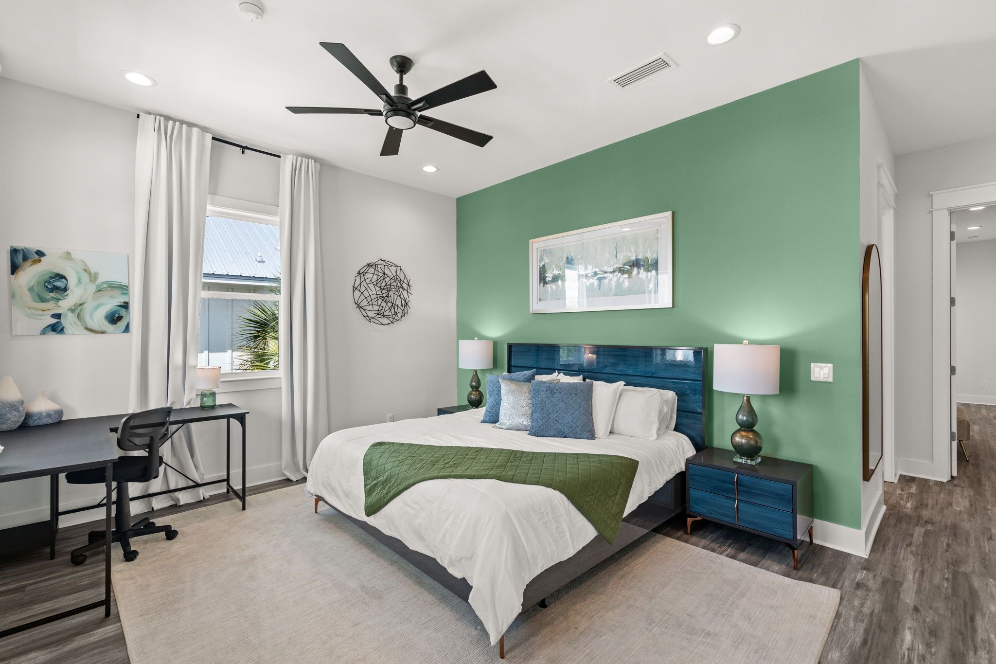 A modern bedroom with a bed, desk, and a ceiling fan.