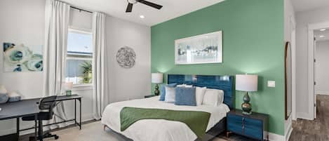 A modern bedroom with a bed, desk, and a ceiling fan.