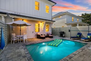 Un jardin à l’arrière d’une maison, avec une piscine, un espace salon extérieur et une terrasse couverte.