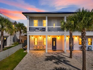 Une maison à deux étages avec un balcon, une allée et des palmiers.