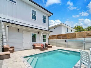 Ein modernes, zweistöckiges Haus mit Swimmingpool, Außenbereich und Holzzaun.
