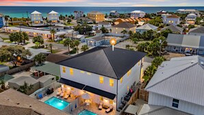 A residential area with a large house featuring a swimming pool, multiple bedrooms, and a view of the ocean.