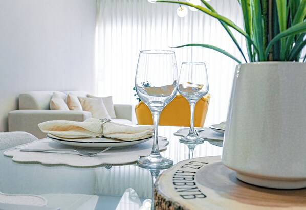 A dining table with two wine glasses and a plate, set in a modern room with a sofa and a potted plant. - Luxury apartment with pool near airport (Santiago de los Caballeros)