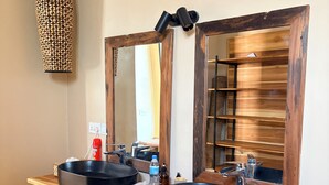 A bathroom with two black sinks, a wooden vanity, a large mirror, and a hanging light fixture. - Shibam Campsite (Naberera)