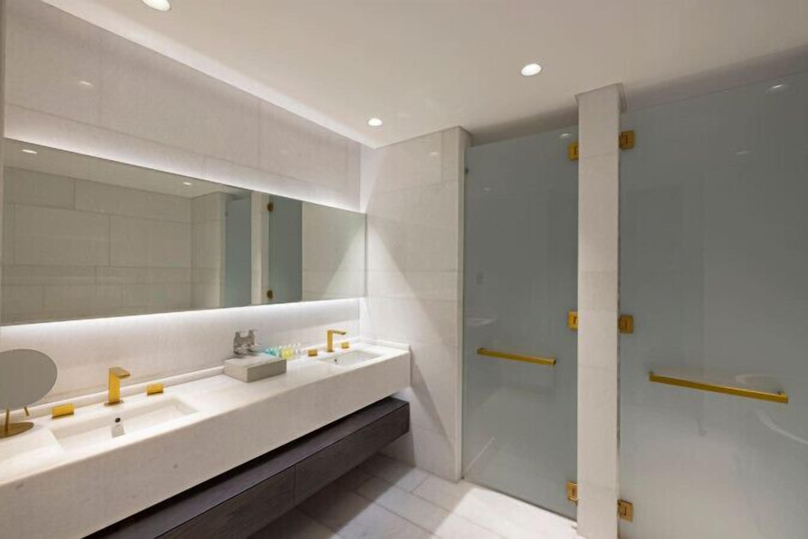Un baño moderno con un tocador blanco, un espejo grande y una cabina de ducha de vidrio.