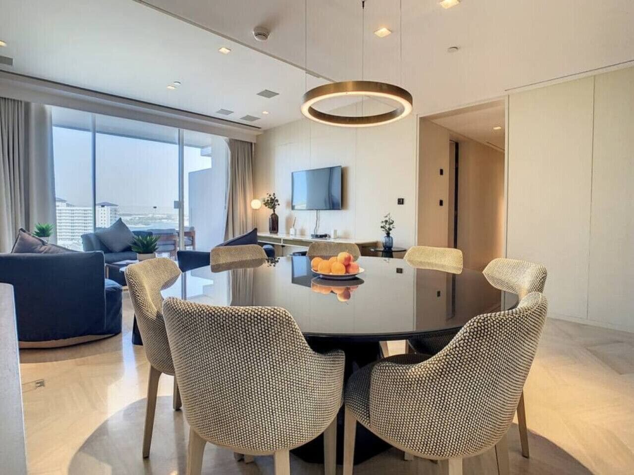 A modern dining area with a round table, four chairs, and a television on the wall.