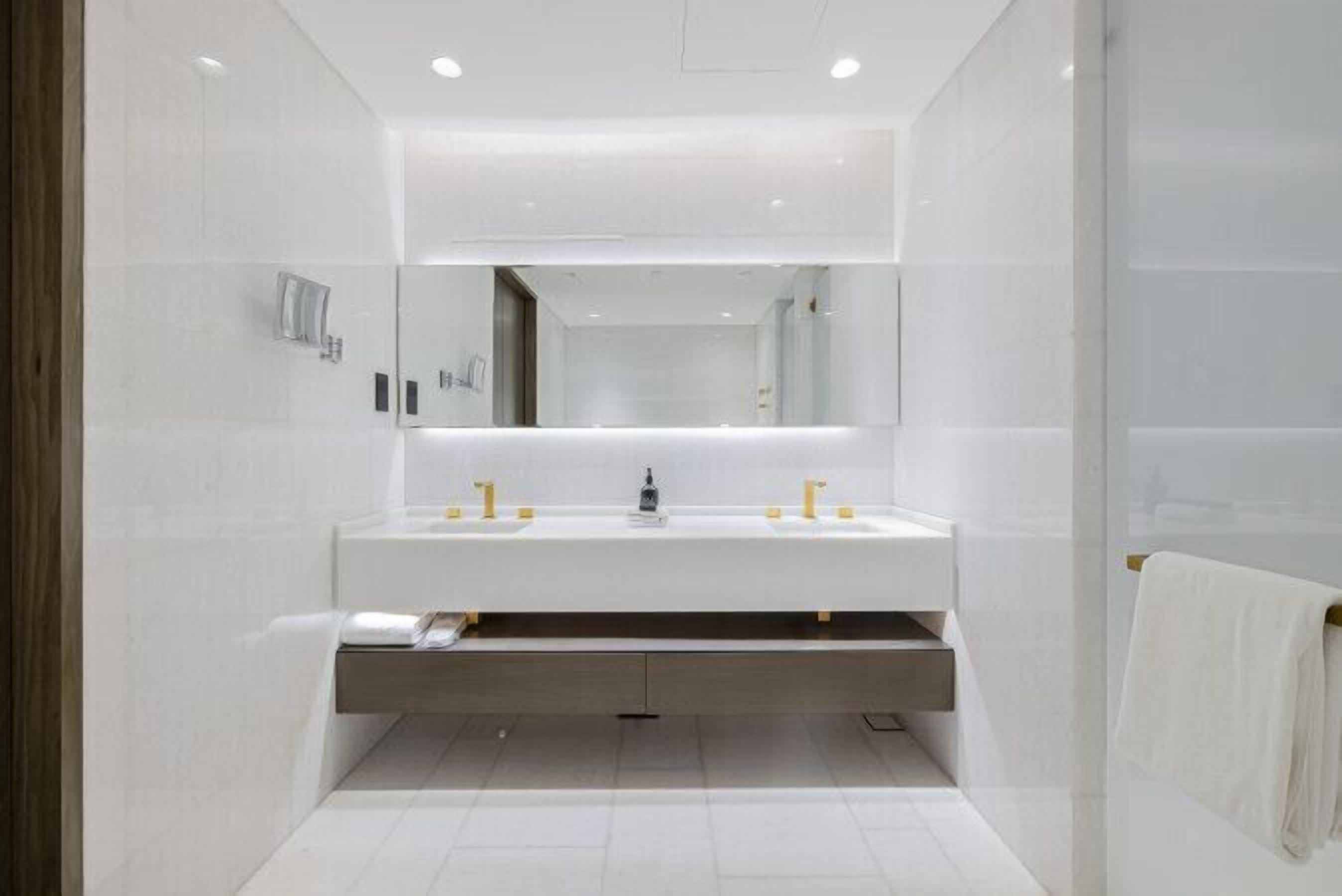 A modern bathroom with a double sink, a large mirror, and a towel rack.