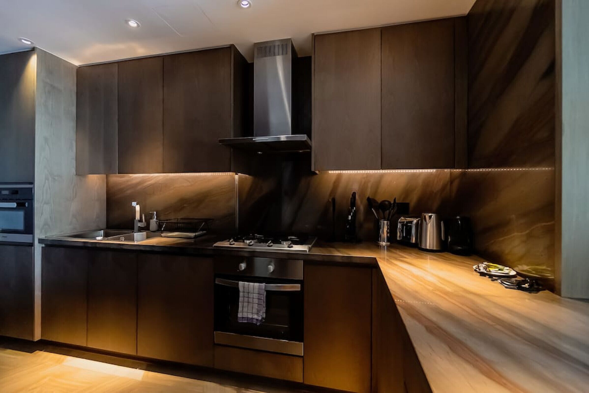 Eine moderne Küche mit dunklen Holzausziehtüren, Edelstahlgeräten und einer Holzausziehtafel.