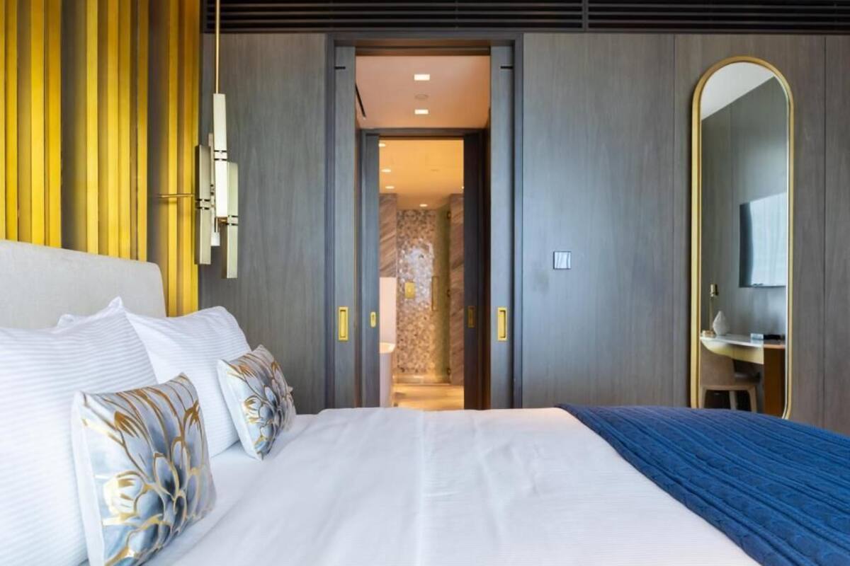 A hotel room with a large bed, a mirror, and a door leading to a bathroom.