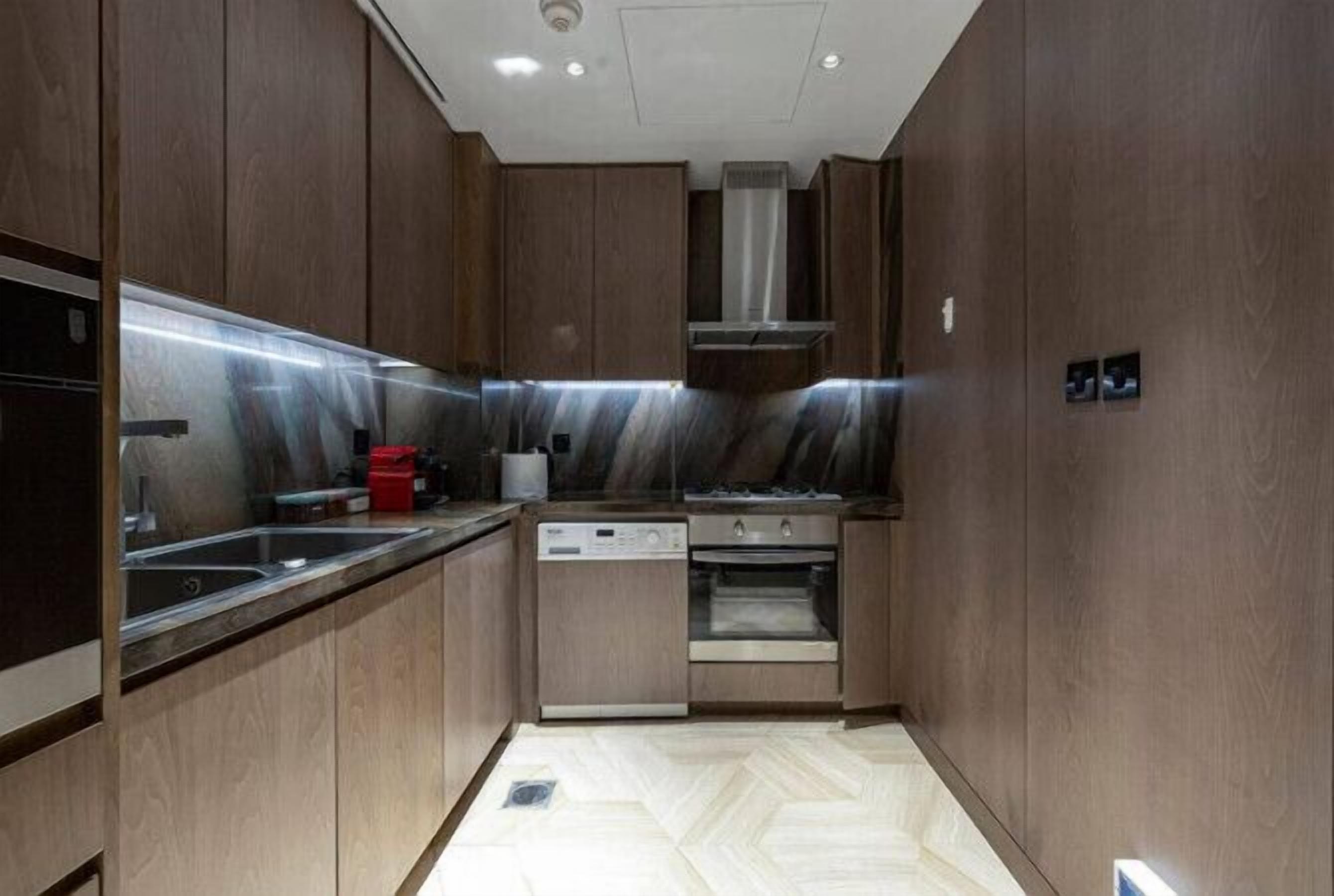 A modern kitchen with wooden cabinets, stainless steel appliances, and a herringbone floor pattern.