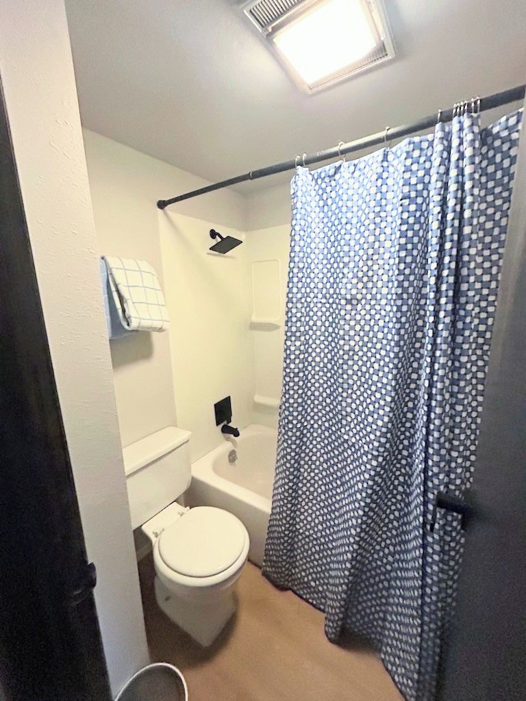 Une petite salle de bain avec des toilettes, une baignoire et un rideau de douche.