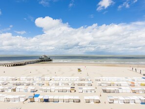 A beach with a pier, beach huts, and a lifeguard tower. - Beautiful apartment on the sea wall (Blankenberge)