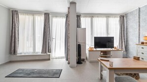 Moderni olohuone, jossa on taulutelevisio, ruokapöytä ja sohva.