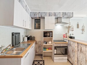 A compact kitchen with white cabinets, a microwave, a stove, and a sink. - Ground-floor flat for 6 persones (Blankenberge)