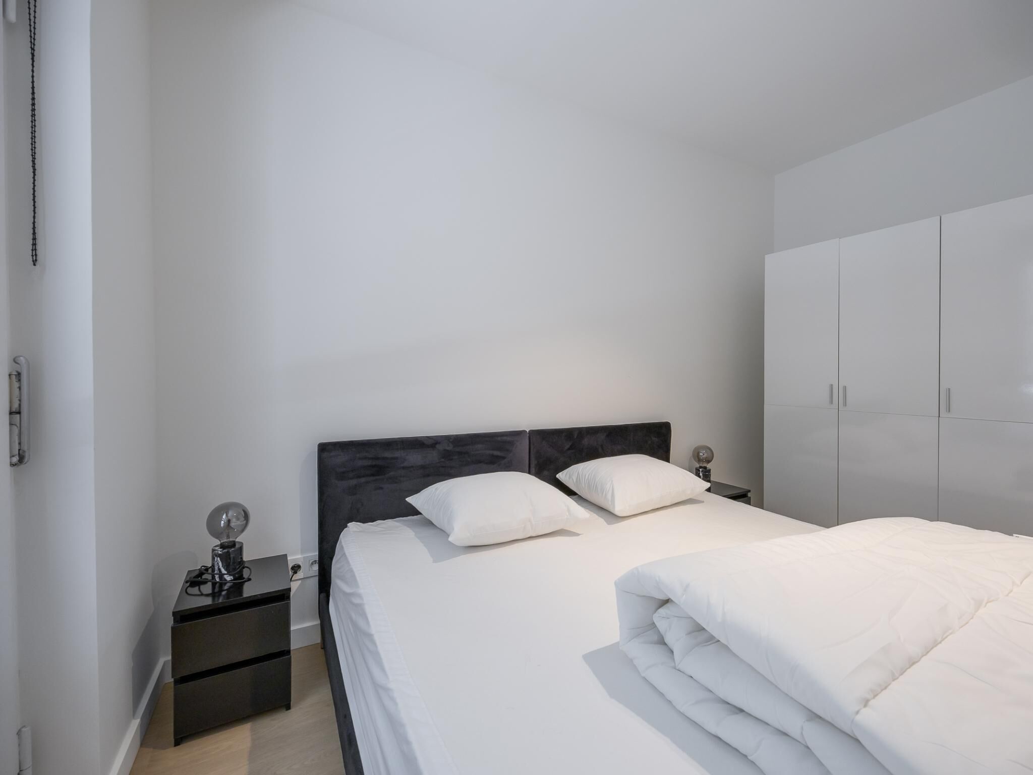 A bedroom with a bed, nightstands, and a wardrobe.
