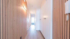 Un couloir aux murs recouverts de lambris en bois, avec un plancher de couleur claire et une porte au fond.